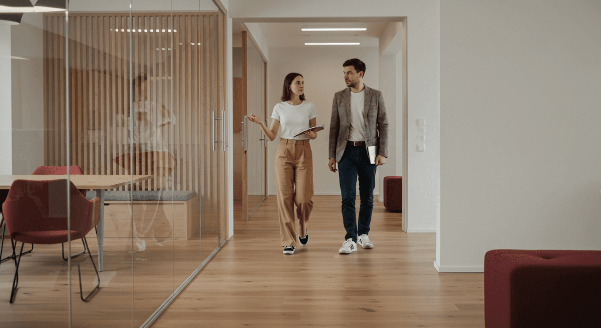 Two professionals in a business meeting, smiling and discussing ideas in half way of office