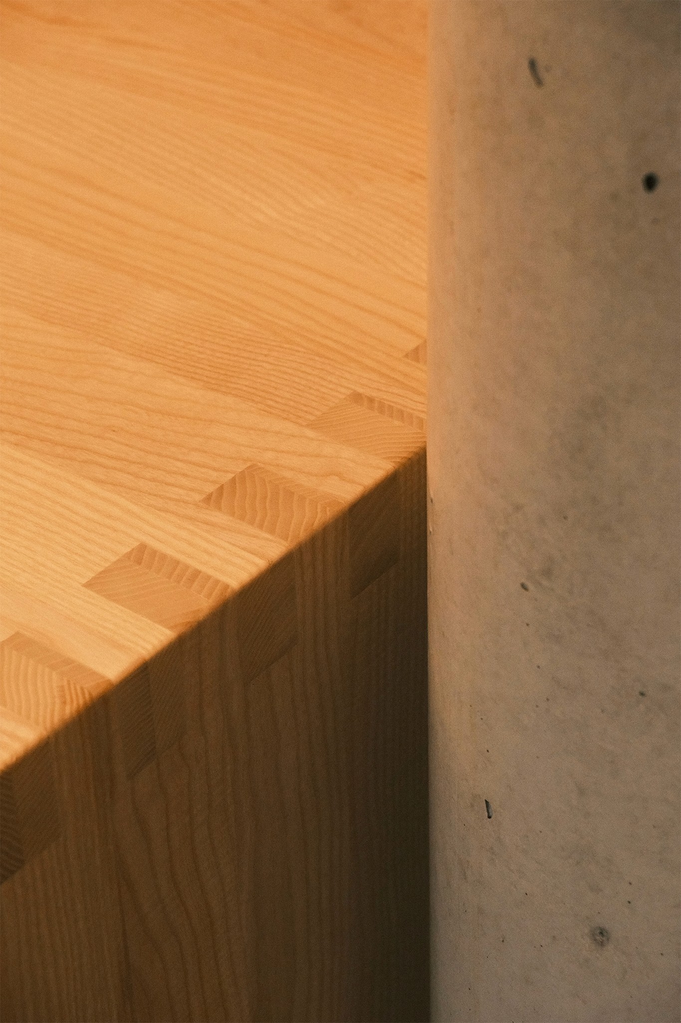 Detailbild eines massiven Holztisch mit Fingerzinken und Betonsäule