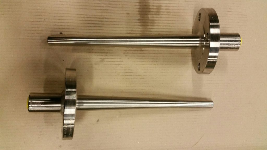 Twee precisie gedraaide thermowell assen met flens in verschillende maten, vervaardigd door machinefabriek Plasma Service Breda