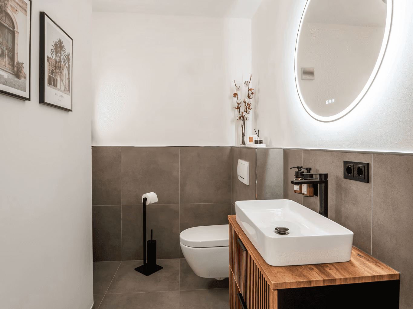 Zeitloses und modernes Gäste-Bad mit schwarzen Fliesen und warmen Holzelementen am Waschbecken von Rosewood Interiors