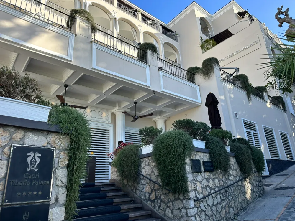 The entrance steps and stone wall at Capri Tiberio Palace, with trailing greenery and its name plaque.
