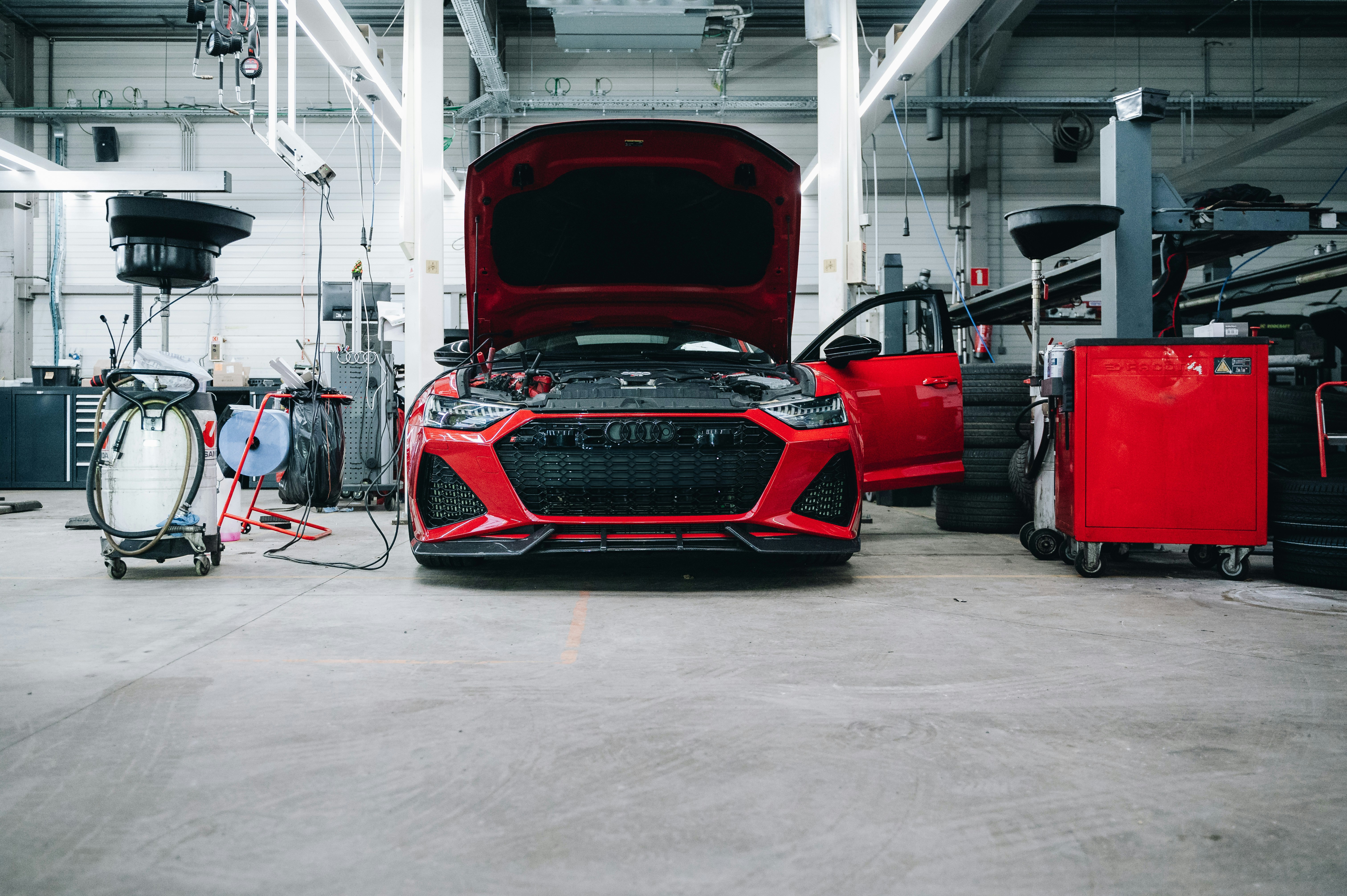 A red car is in a garage for repairs.