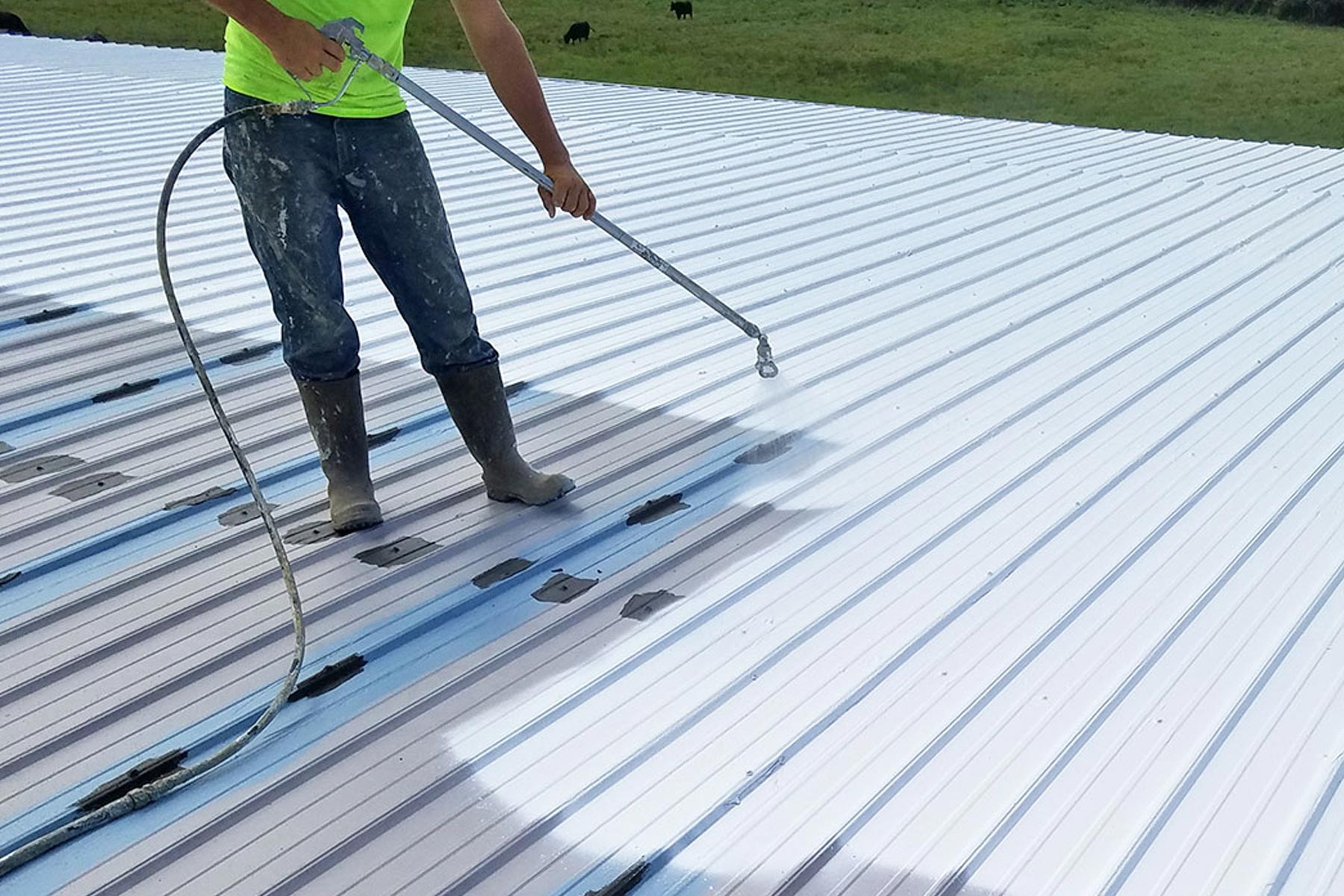 Spraying on silicone coating on a large metal roof. 