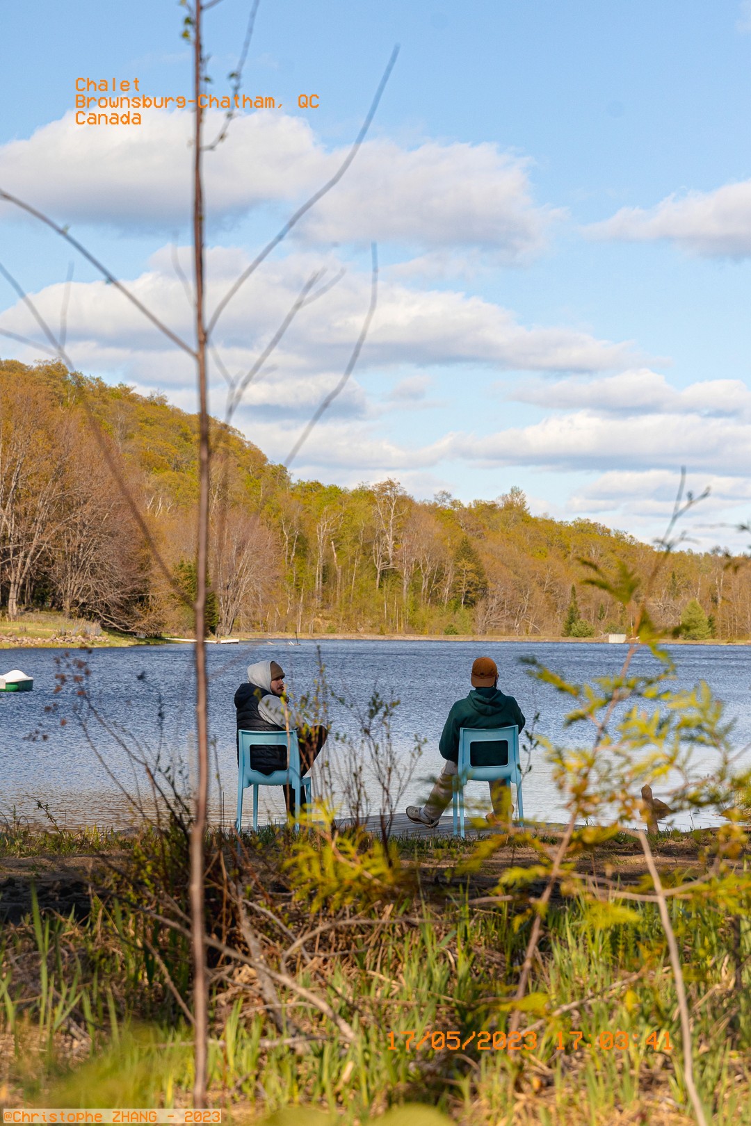 Deux personnes assises au bord d’un lac, entourées de forêt printanière.