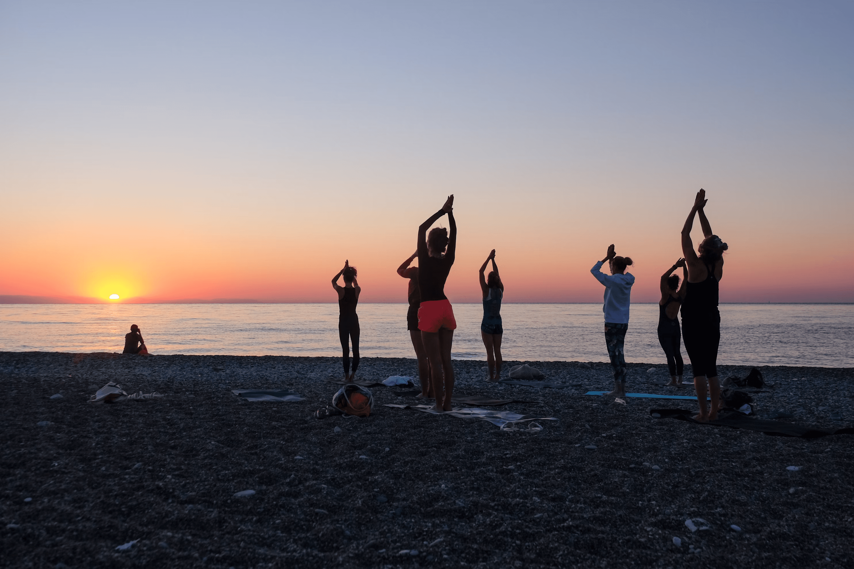 A group of people praticing yoga on the beach in the morning