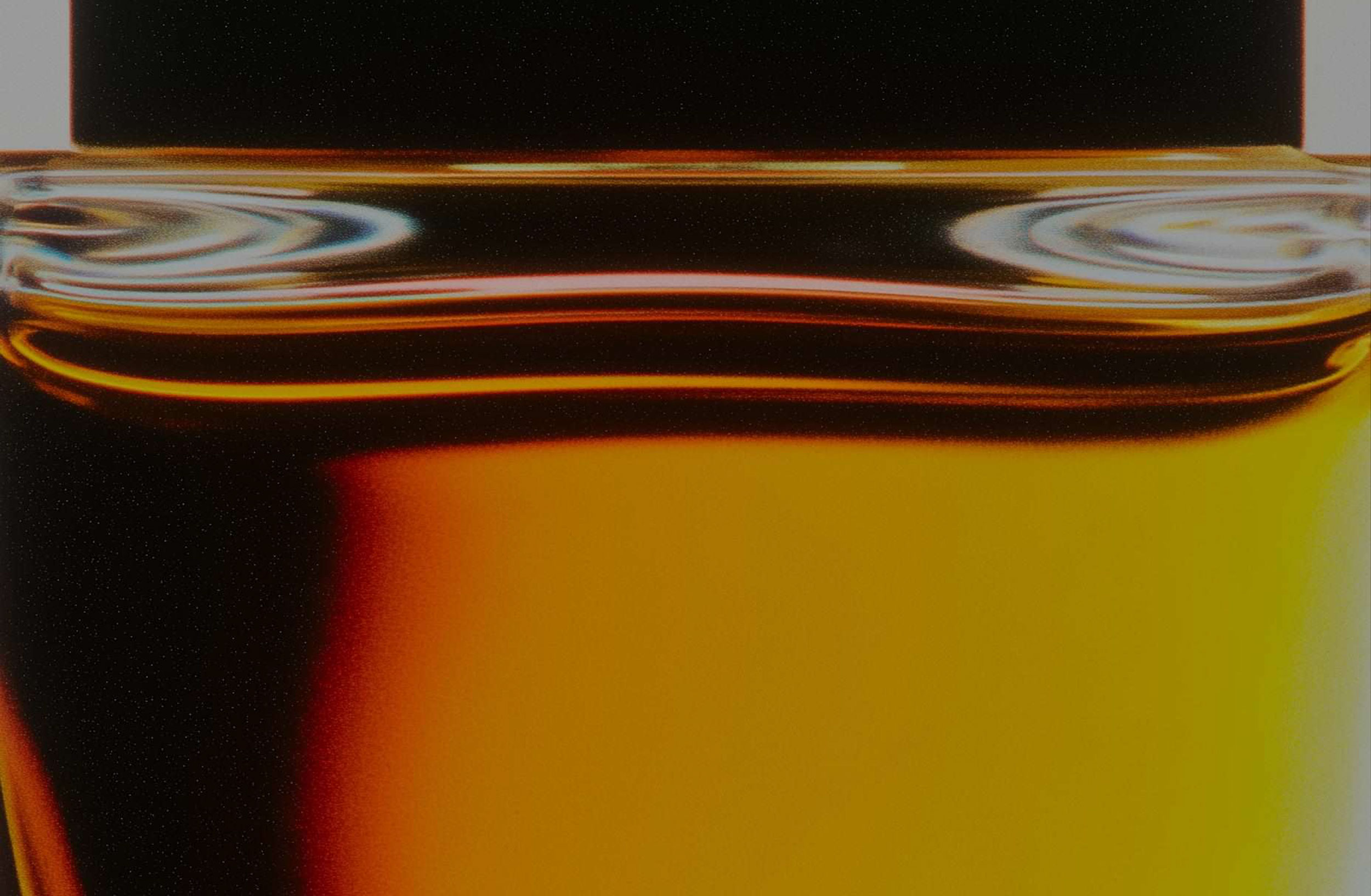 Close-up of amber liquid in a glass container, with reflections on the surface.