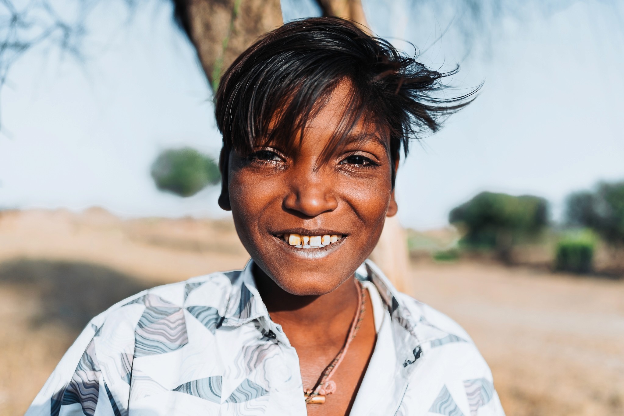 a girl wearing her school clothes picking fruits from a tree in a remote rural village in rajasthan