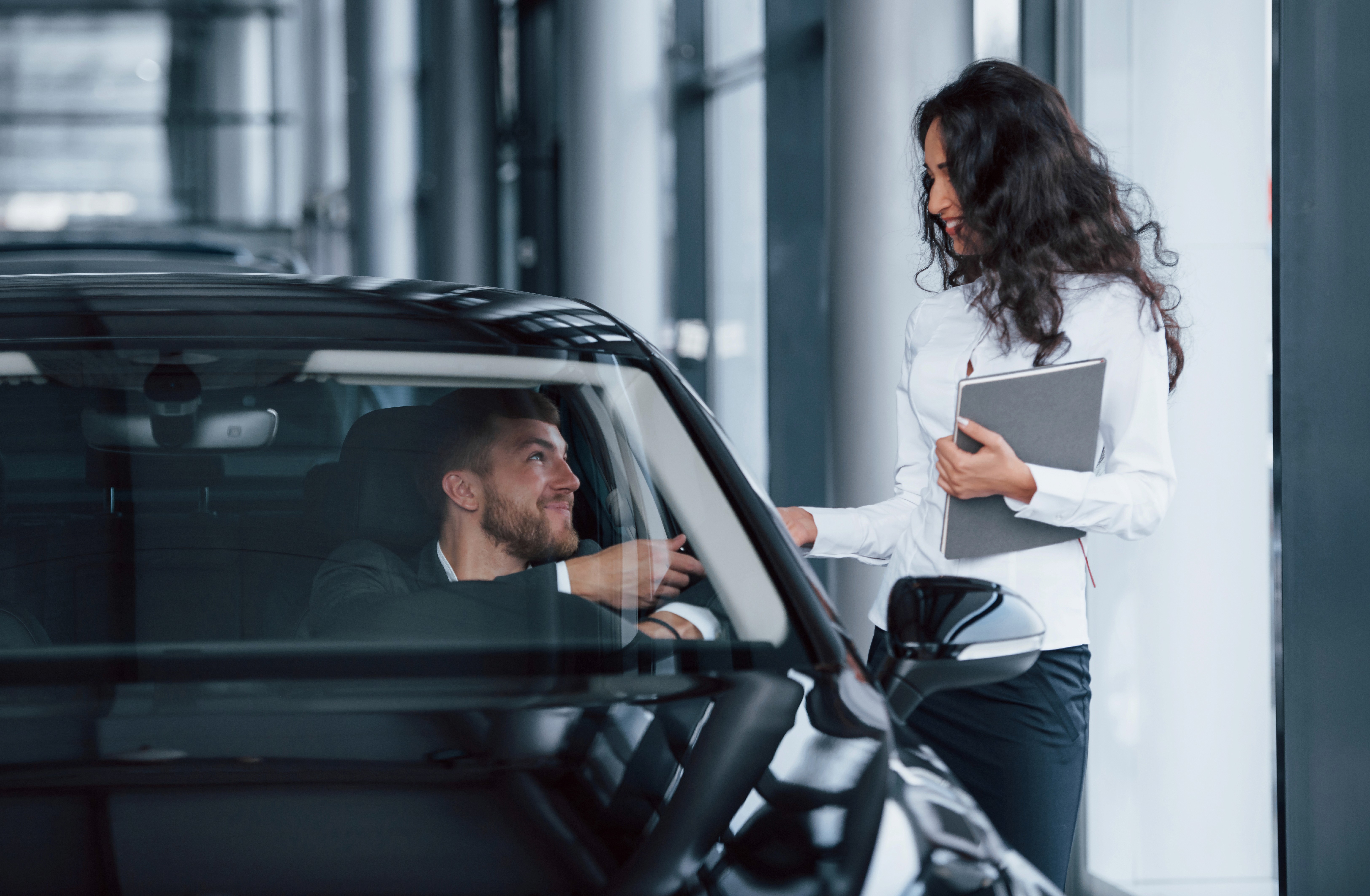 A cheerful car renter talking to an excited young child ready to drive a sportscar, ideal for car rental family moments.