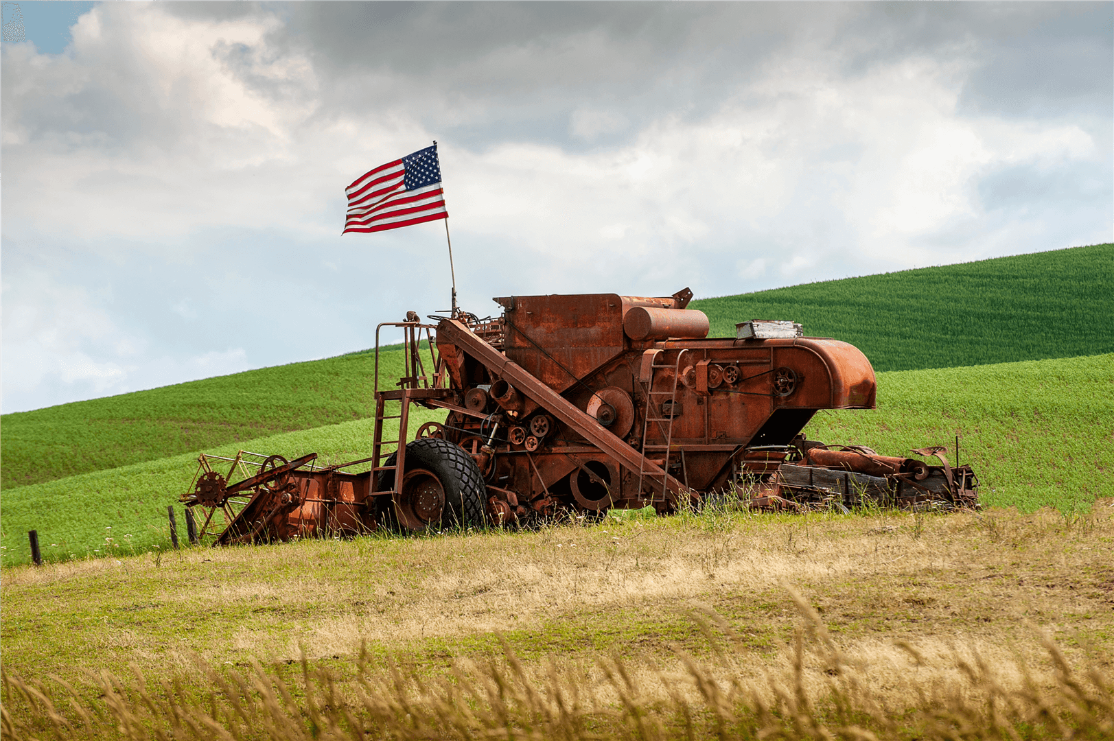 Rusty combine harvester with American flag in field