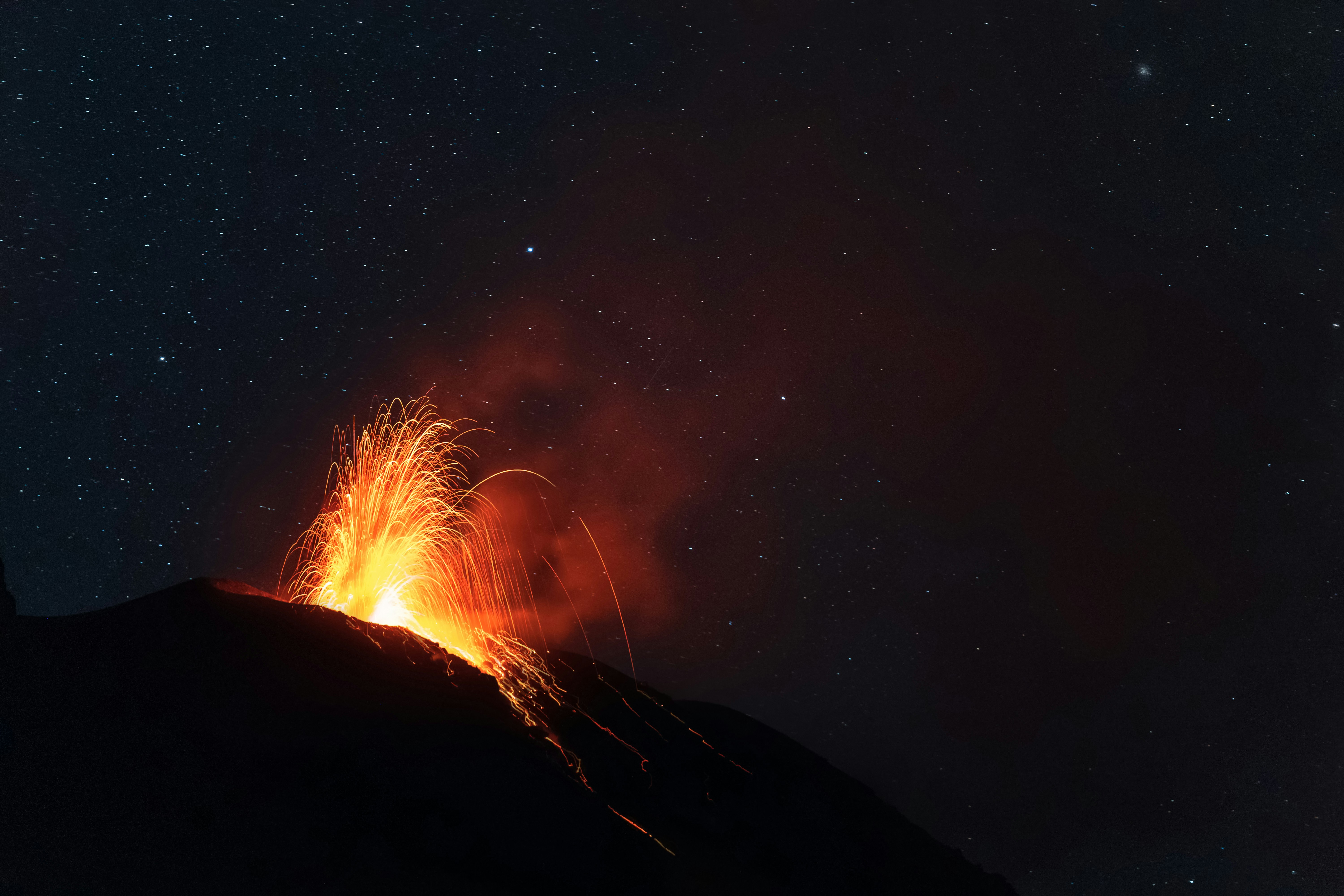 Volcano erupting with glowing lava at night