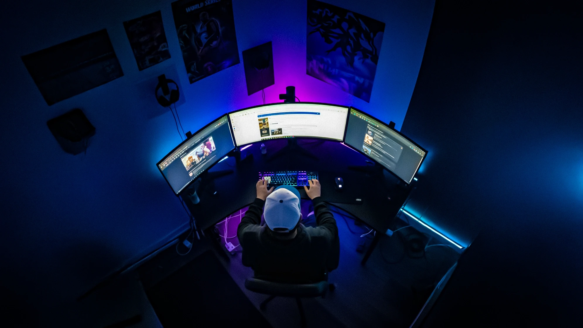 "Overhead shot of a gamer in a dark room surrounded by multiple monitors and LED lights. Represents the isolation and digital lifestyle of the target audience, establishing the context for a relatable patient story in the gaming community.