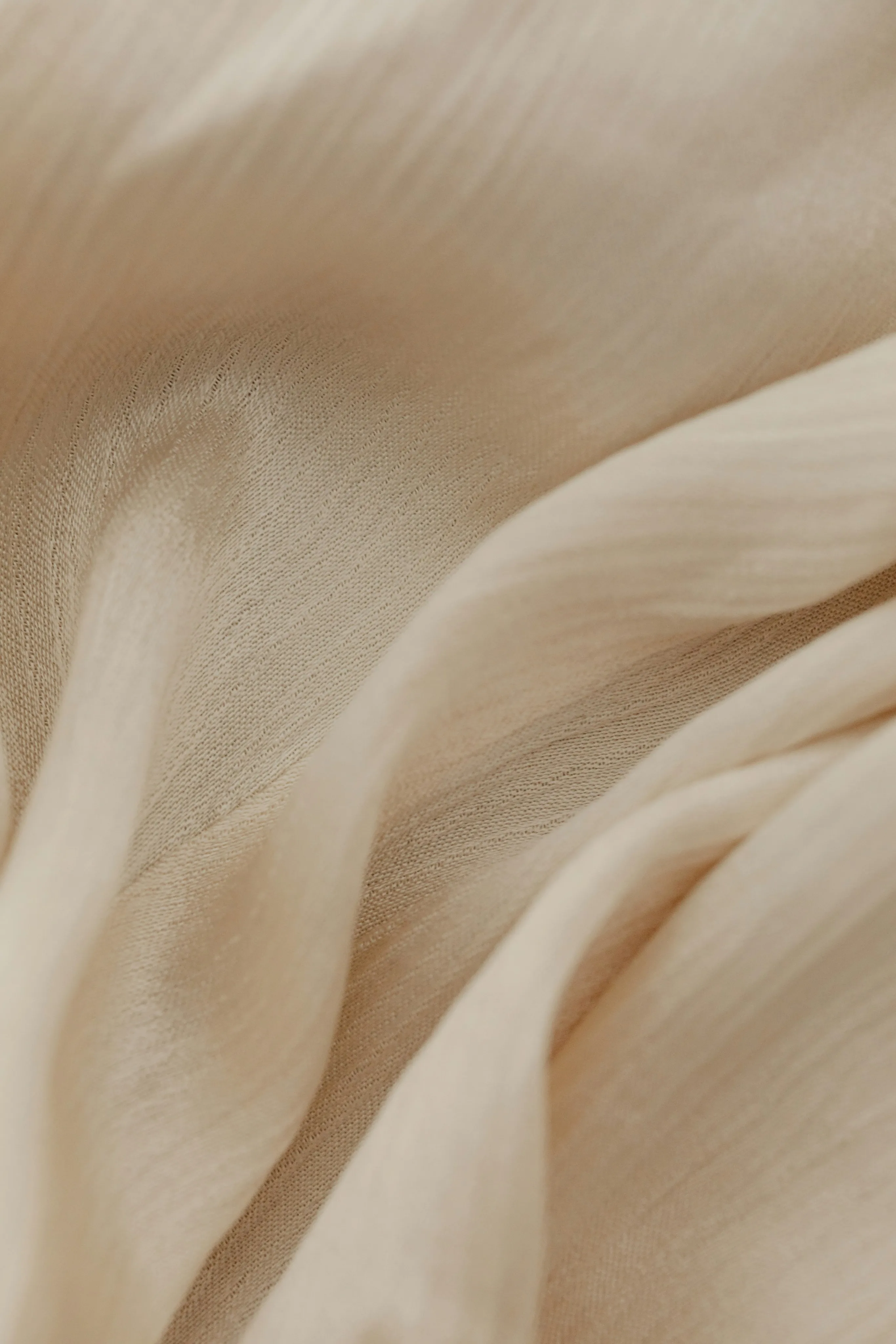 Detail of pleated cream silk fabric texture, showcasing the airy and elegant craftsmanship of high-end sustainable fashion.