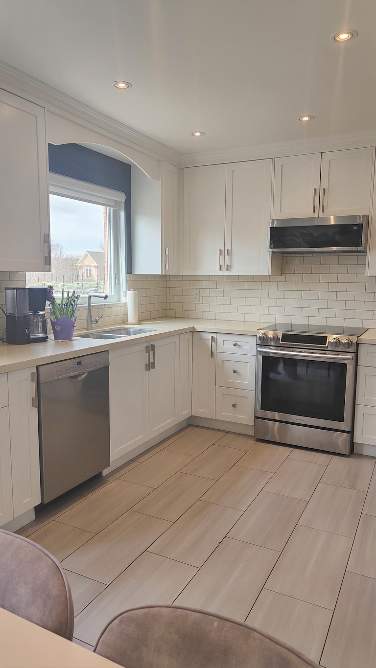 All-white kitchen: painted lower cabinets, warm white subway backsplash, cream quartz counters