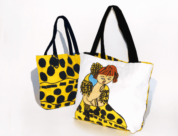 Two tote bags are displayed against a white background. The bag on the left is yellow with black polka dots and features black handles. The bag on the right is white with a black strap and displays a colorful illustration of a woman with red hair and a patterned skirt. Both bags are positioned at an angle.