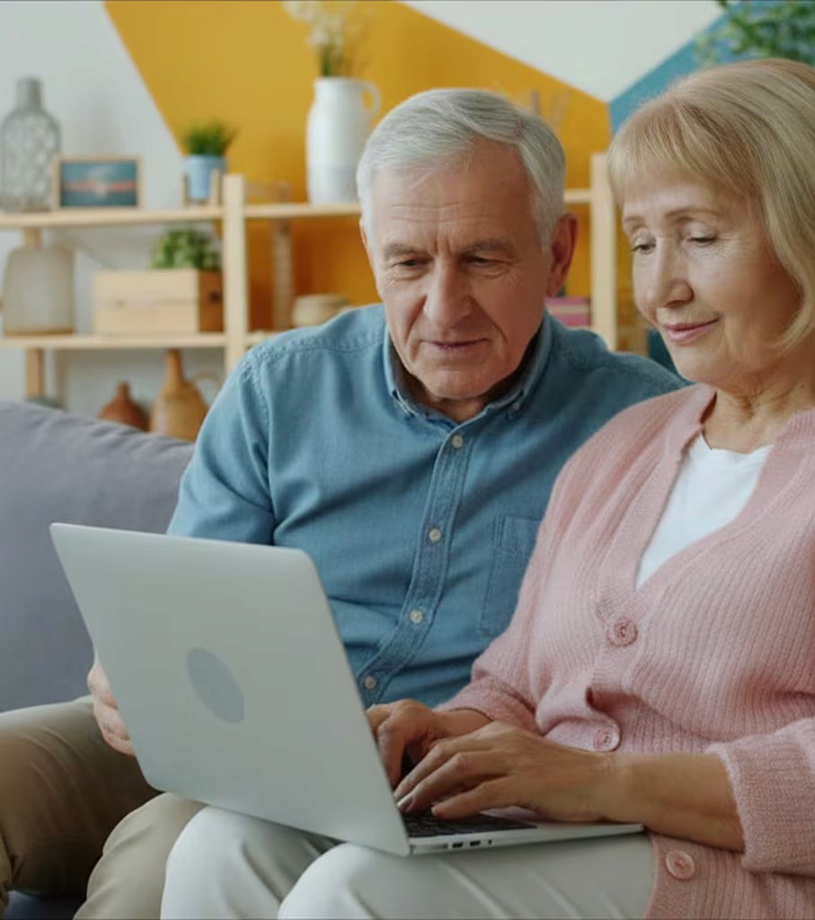 Smiling elderly couple embracing in a kitchen. Woman with white hair touches man's shoulder.