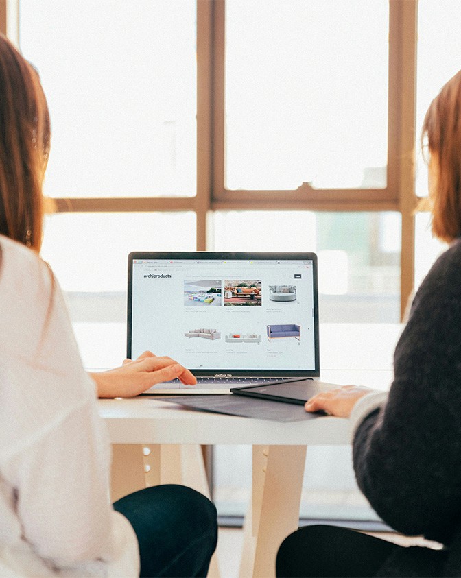Two women having a meeting together with a laptop placed in between them.