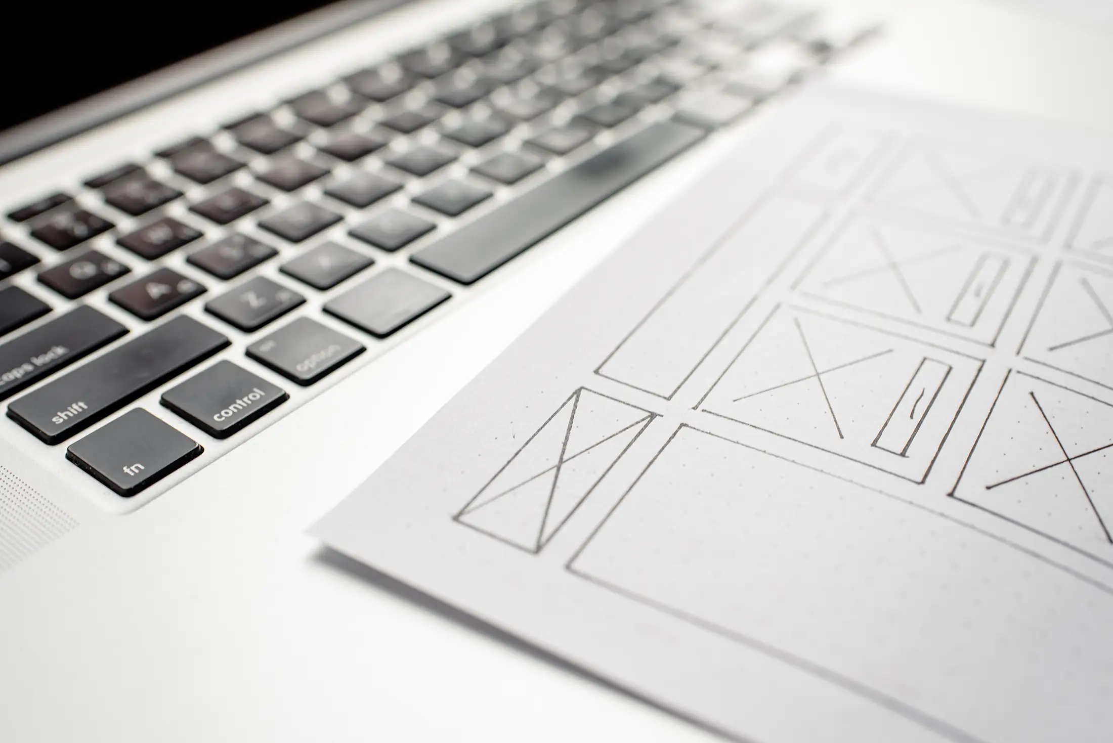 laptop keyboard with website design draft on paper