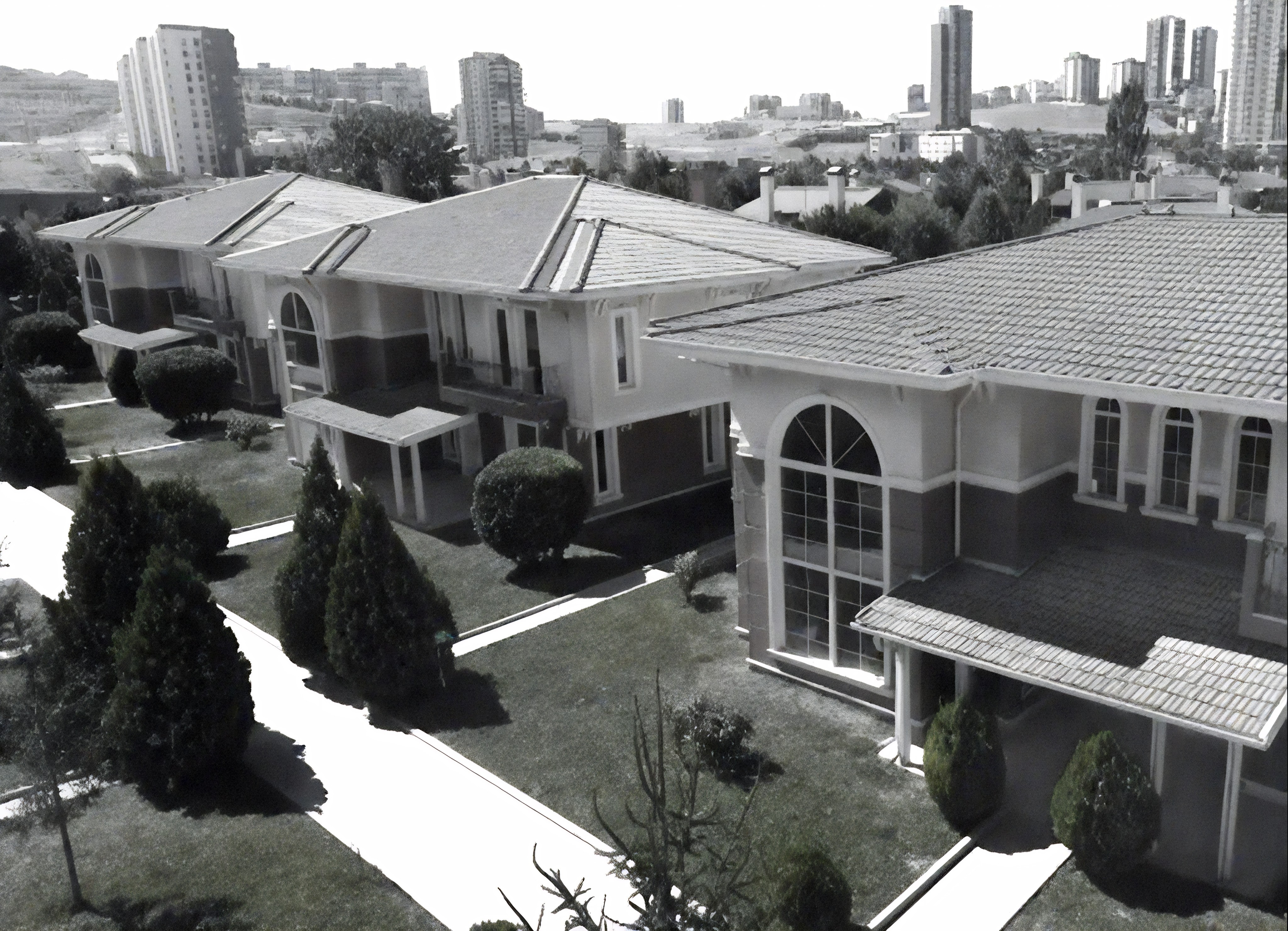 Modern red brick apartment or office building viewed from below against a blue sky, showcasing its geometric architecture with evenly spaced windows and balconies.