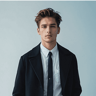 A man wearing a black coat and tie stands confidently, exuding a formal and professional appearance.