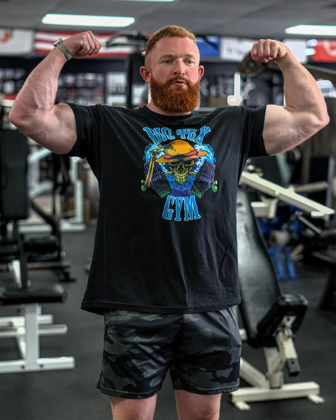 Big Tex Gym member flexing in Big Tex branded shirt at Big Tex Gym, Austin TX