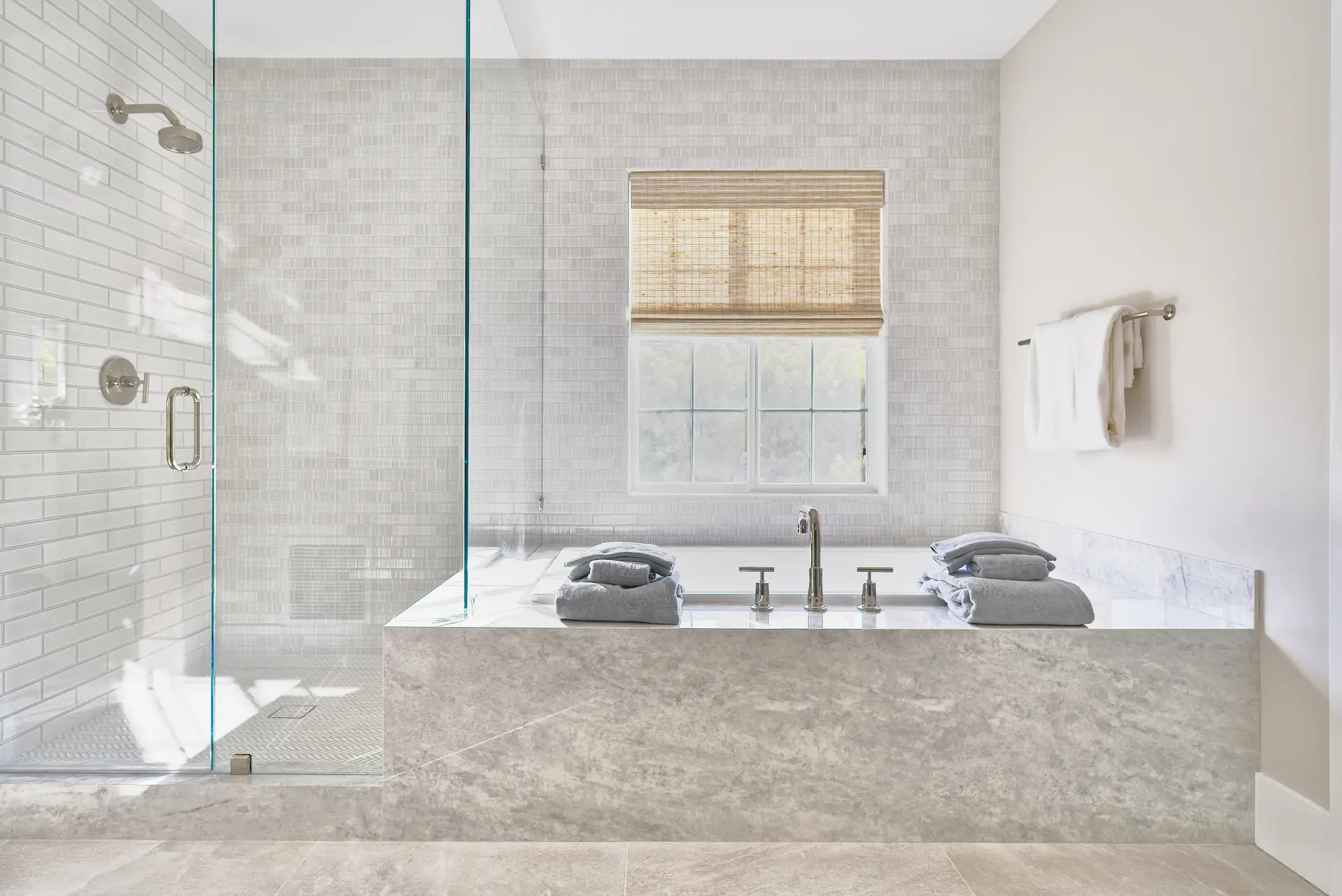 View of the tub and shower area in the primary bathroom, showcasing the fixtures and tile work in the Irvine Contemporary Coastal Remodel. Photo by Todd Huge.