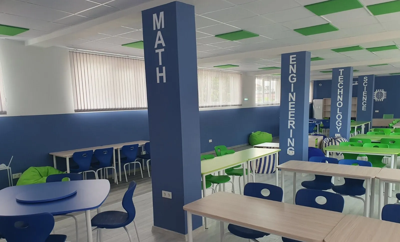 Modern learning space with blue and green school chairs, classroom tables, and subject-themed columns