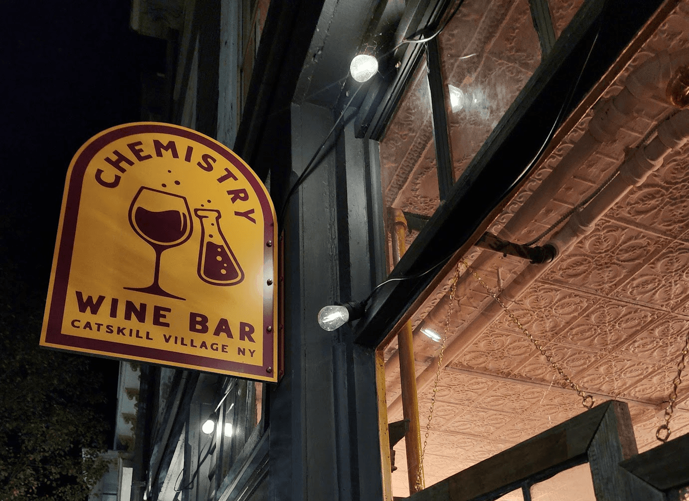 Picture of street sign for Chemistry Wine Bar in Catskill, New York — bold, brand style logo with decorative sans serif typography, designed by Will Lefkovich.