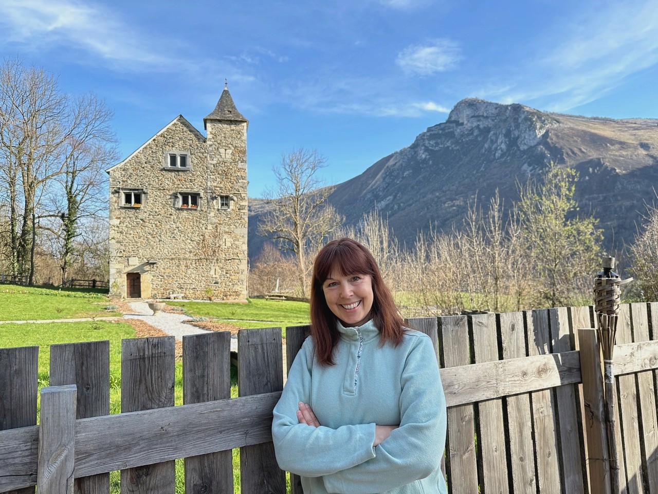 Trish, the American-born owner of Château de Gère, smiling in front of the historic lodge. Trish collaborates with The Basque Way to orchestrate exclusive, immersive stays.