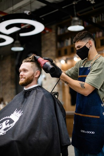 Layered Haircut in our Barbershop: A skilled barber cutting long, layered hair for client in a modern barbershop. The setting is bright and welcoming, with plants and contemporary decor enhancing the friendly atmosphere.