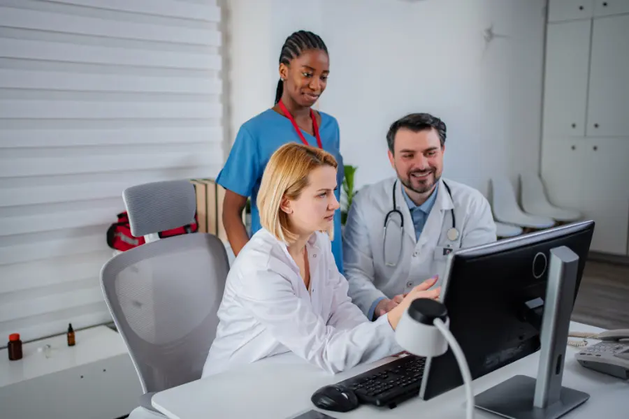 ai in medicine shown as a team of healthcare professionals collaborating around a computer screen in a bright office.