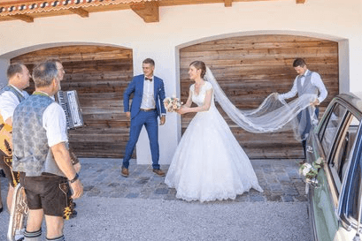 Braut wird beim Richten des Schleiers vor der Hochzeit von Helfern unterstützt