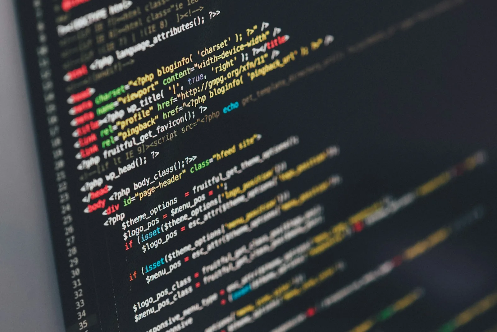 Close-up of a monitor showing colour-highlighted HTML and PHP template code in a dark code editor