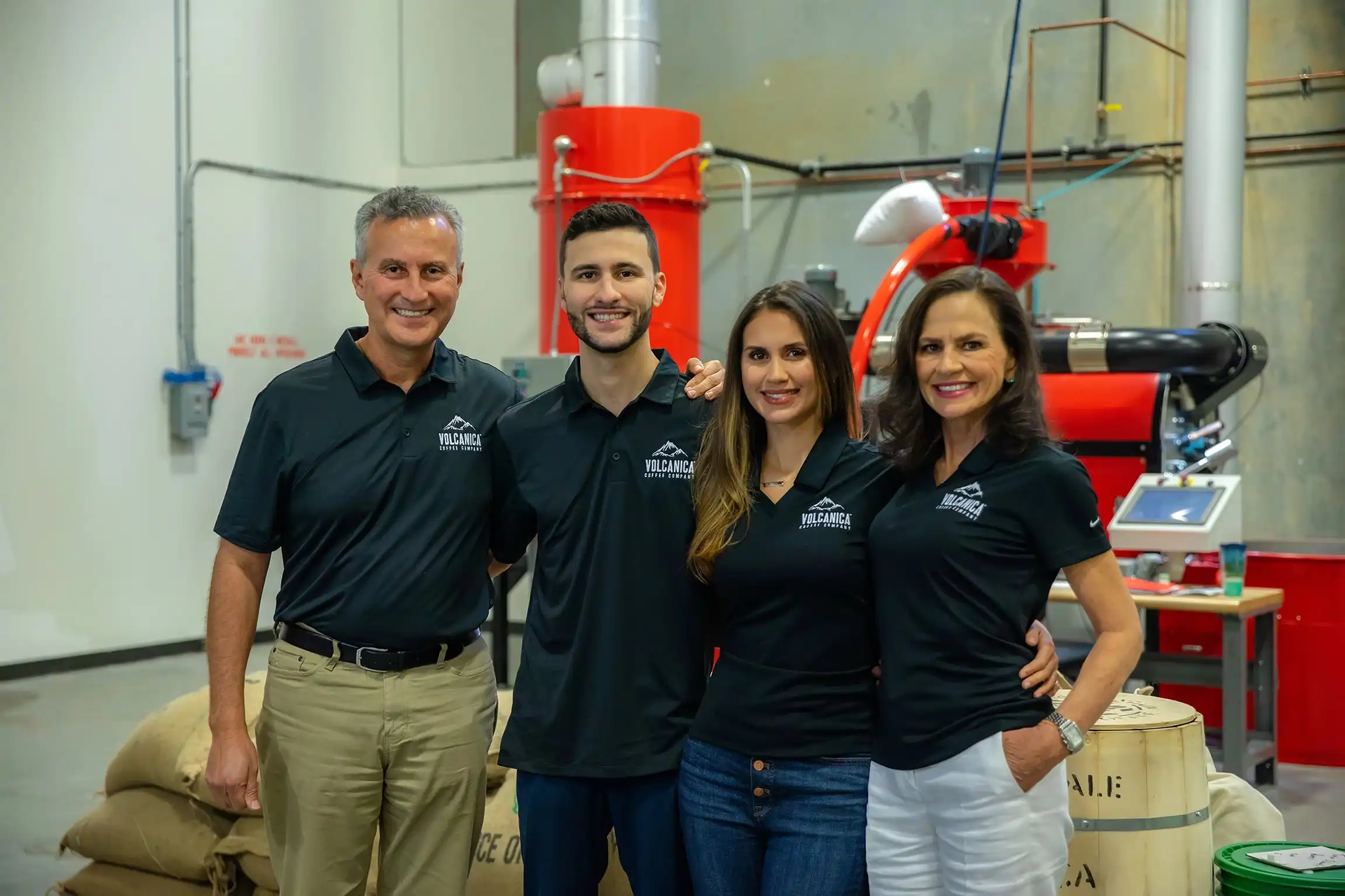 The Volcanica Coffee Company family in their state of the art coffee warehouse, with coffee bags and red machinery, matching their branding, the Contreras family.