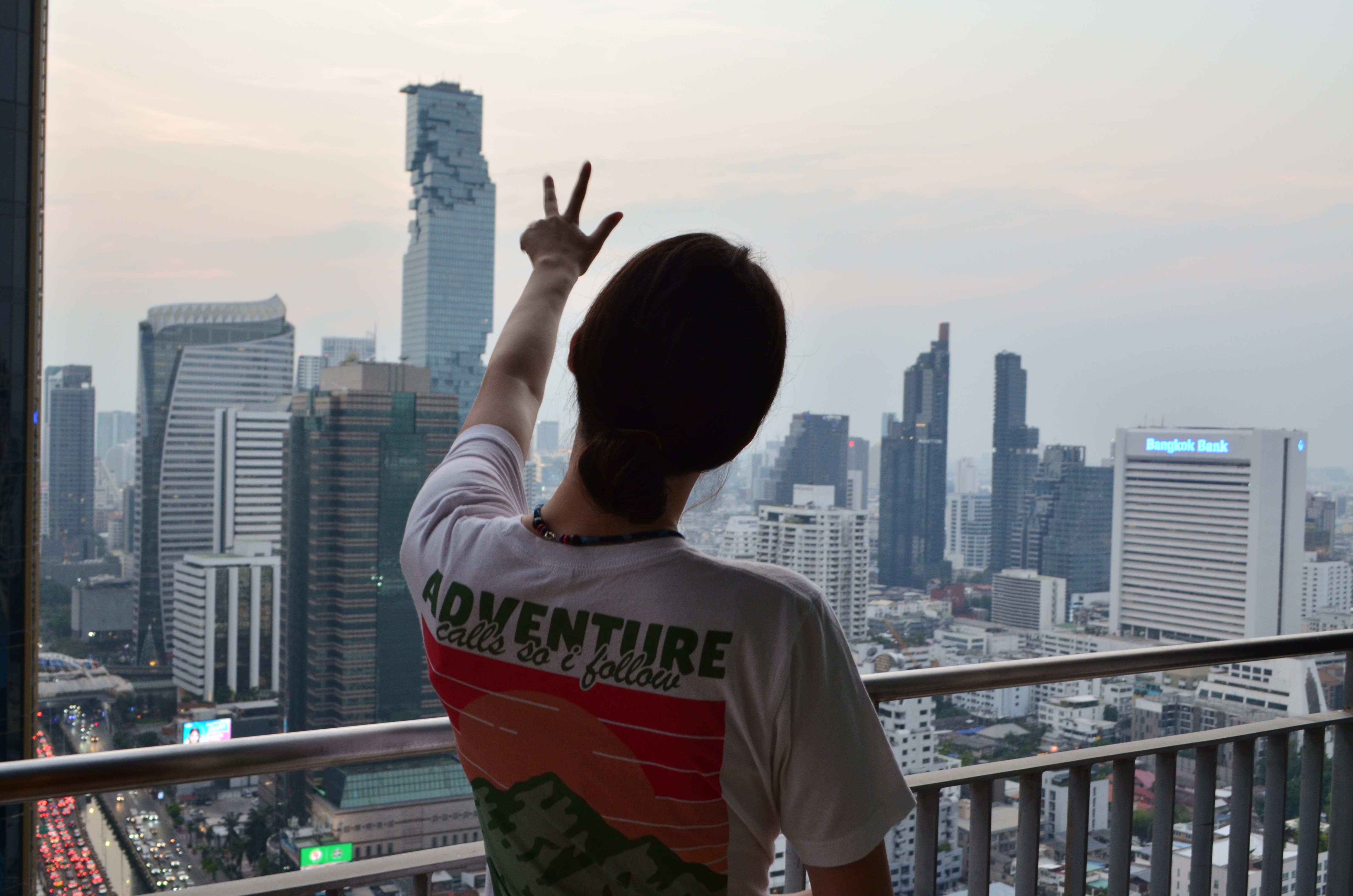 Smiling young man with short hair poses against a dark background, wearing a green button-up shirt.