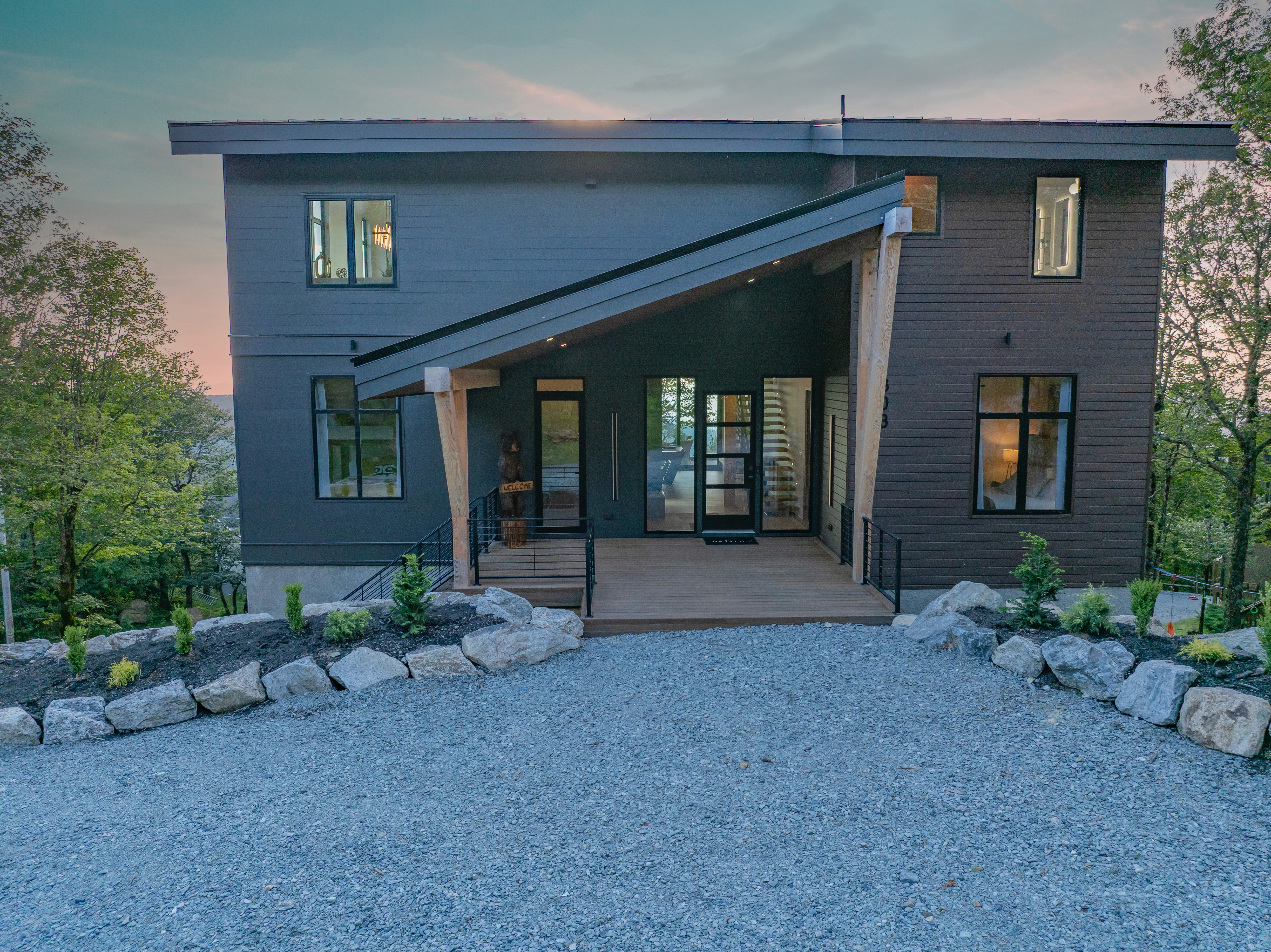 A striking aerial photograph capturing the modern Beech Harmony cabin nestled within a lush, green mountain forest