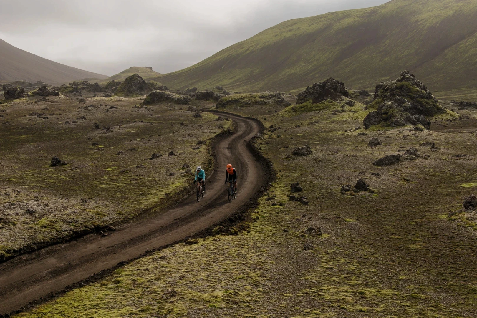 Two people pedal on smooth gravel in the highlands of Iceland
