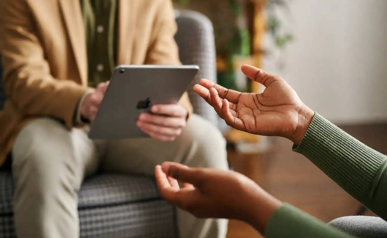 Healthcare professional reviewing information on a tablet during a patient consultation.