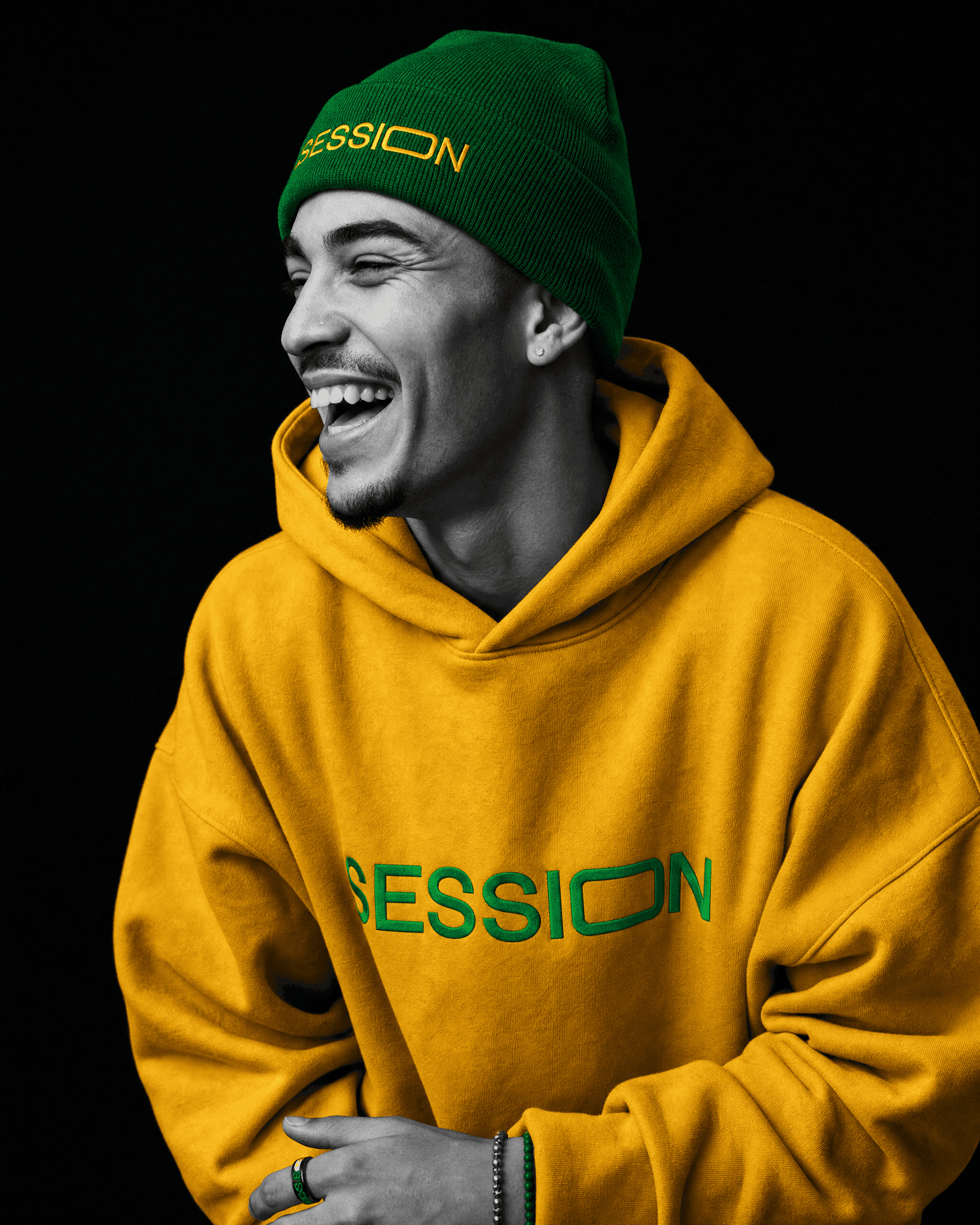 Man laughing in a green Session Zone beanie with yellow lettering and a yellow SESSION logo hoodie.