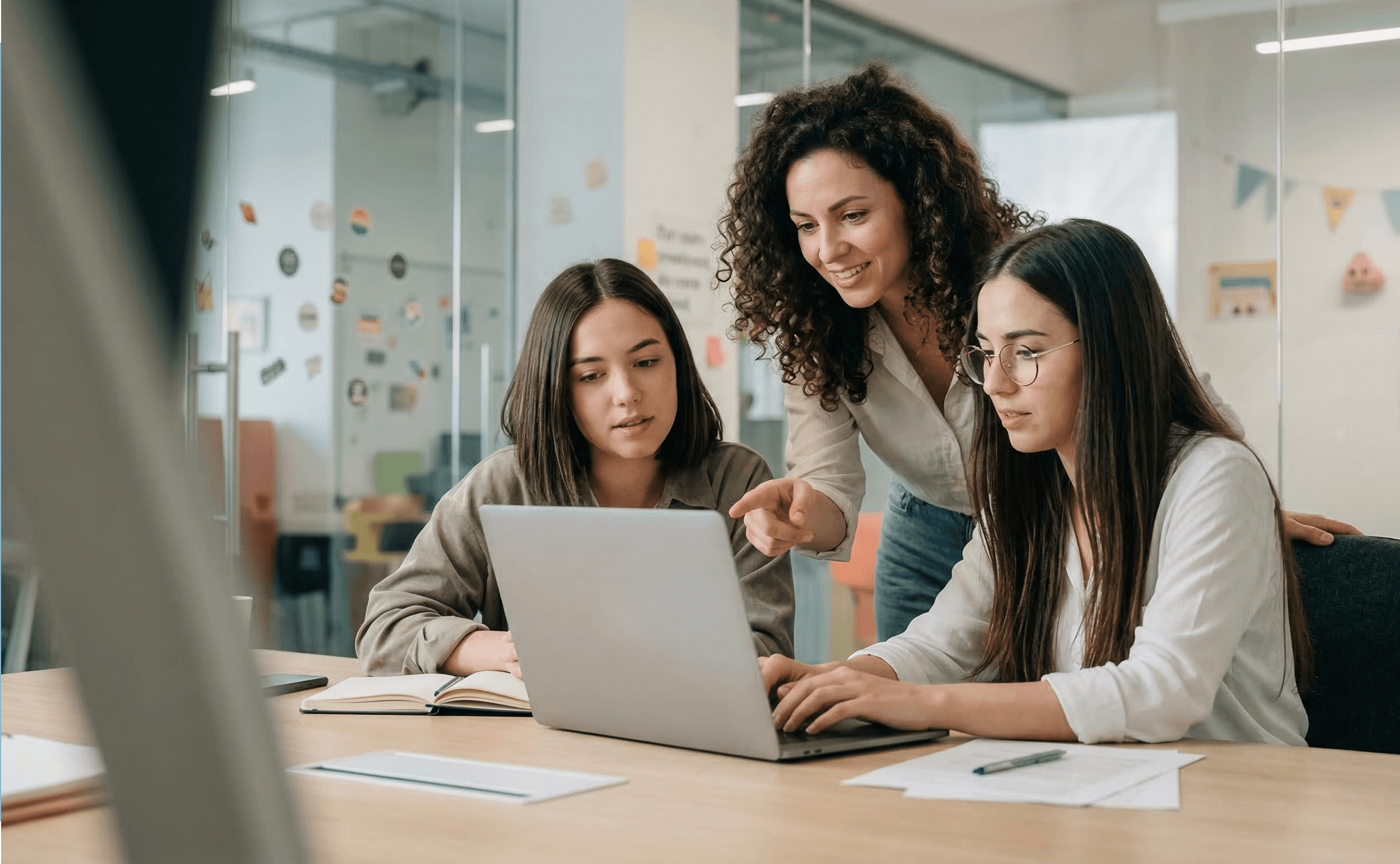Designer guiding two teammates while working on a laptop