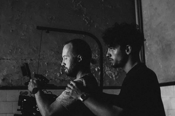 Reilin holding the shoulders of a camera man to support