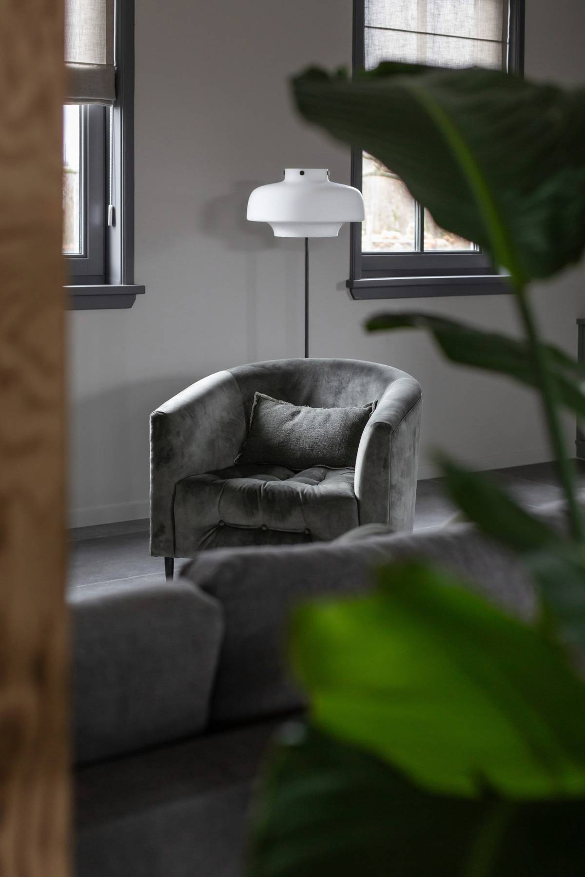 zithoek schuurwoning en vergrijsd groen fauteuil en scandinavische lamp
