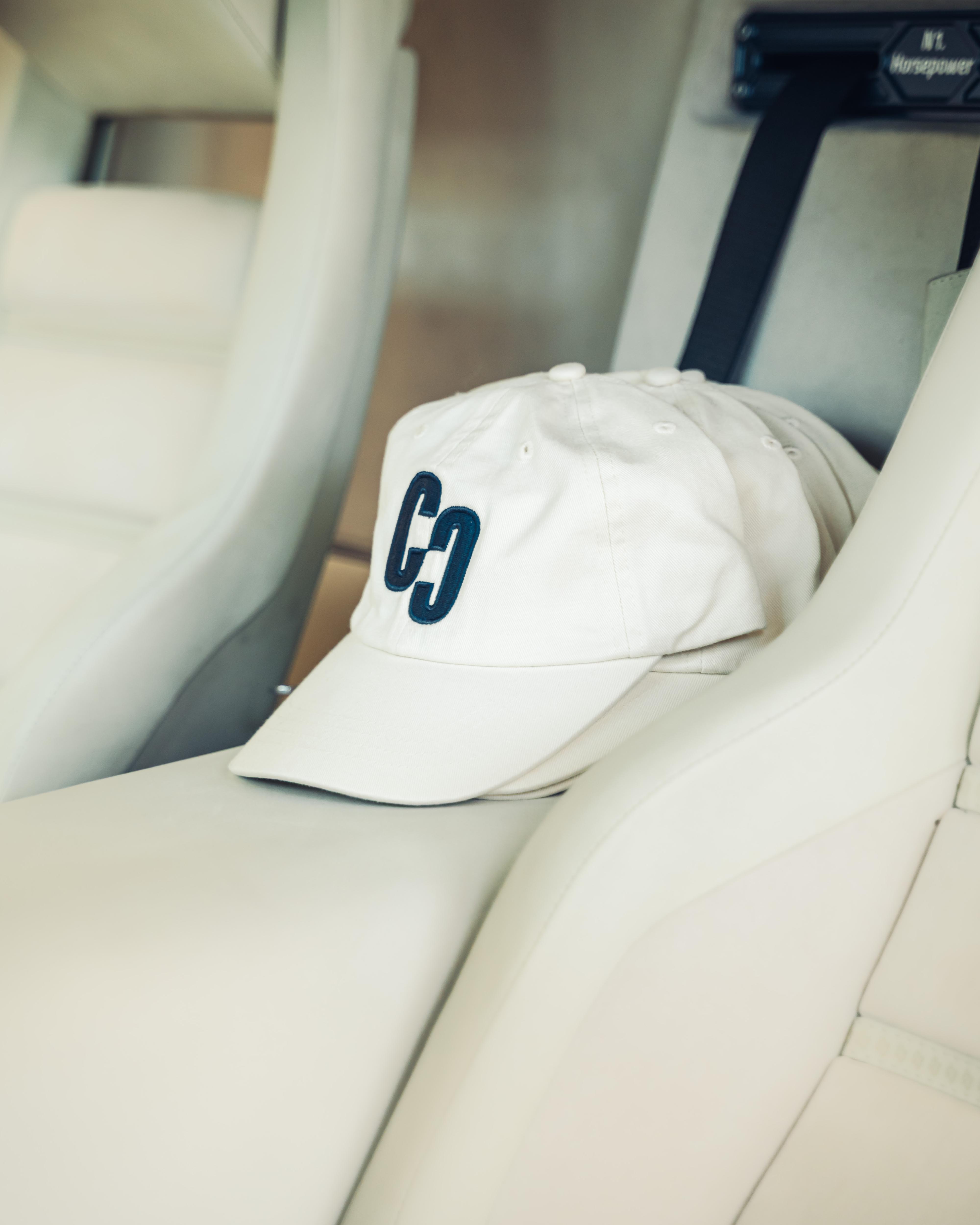 Cappello bianco con logo eccentrica poggiato su sedili sportivi in pelle