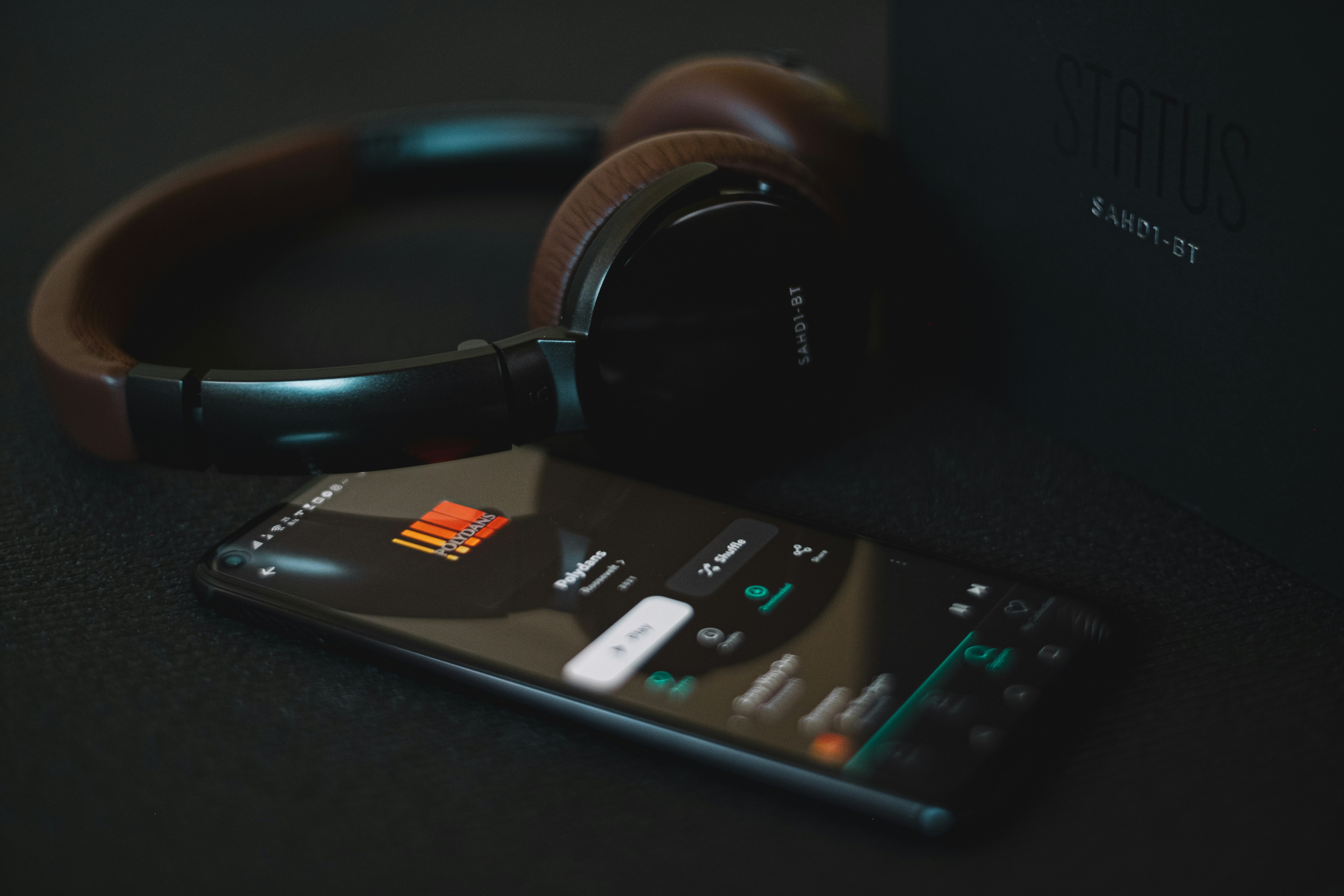 casque audio à côté d’un téléphone avec l’application Spotify ouverte en lecture musicale