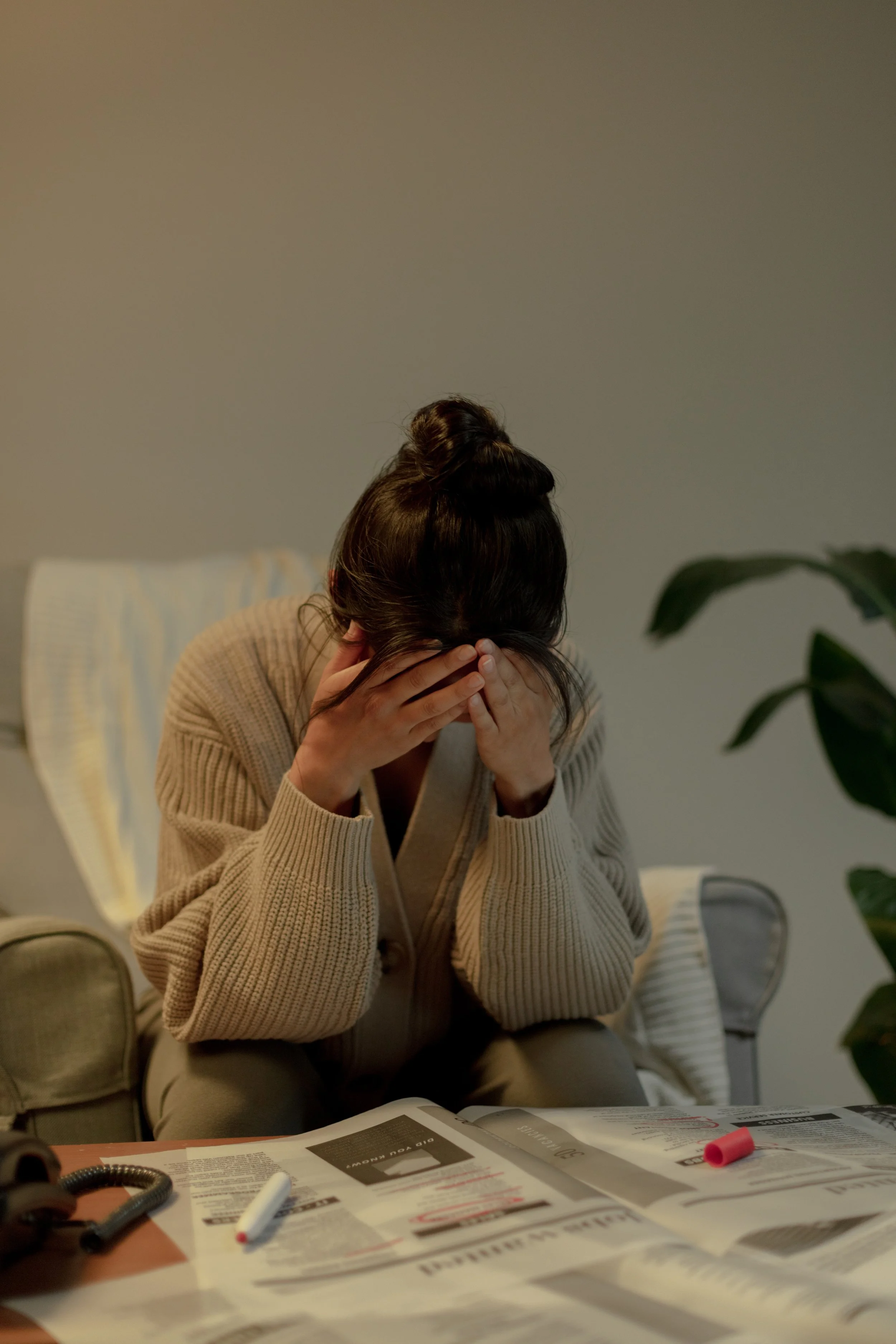 An Asian woman holds her head in her hands