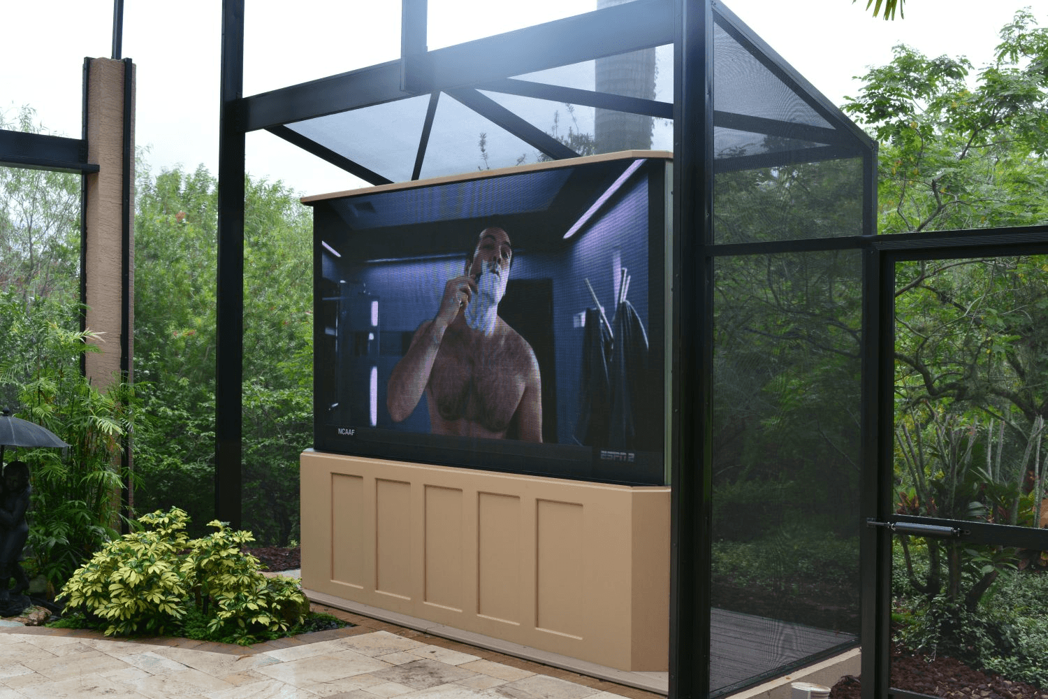 Outdoor screen showing man shaving, surrounded by greenery.