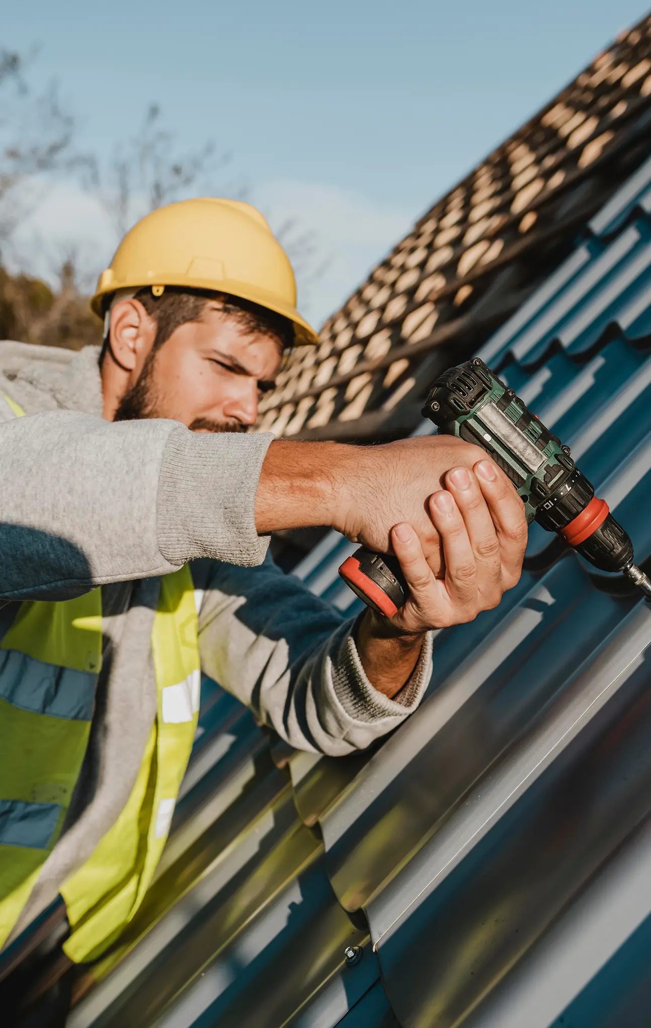 Roofer using a drill on a metal roof