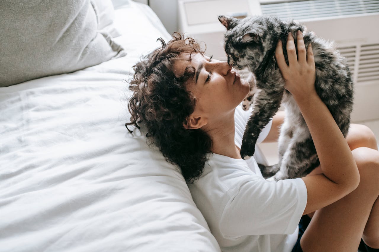 Picture of a woman holding a cat up in the air and kissing it on the nose