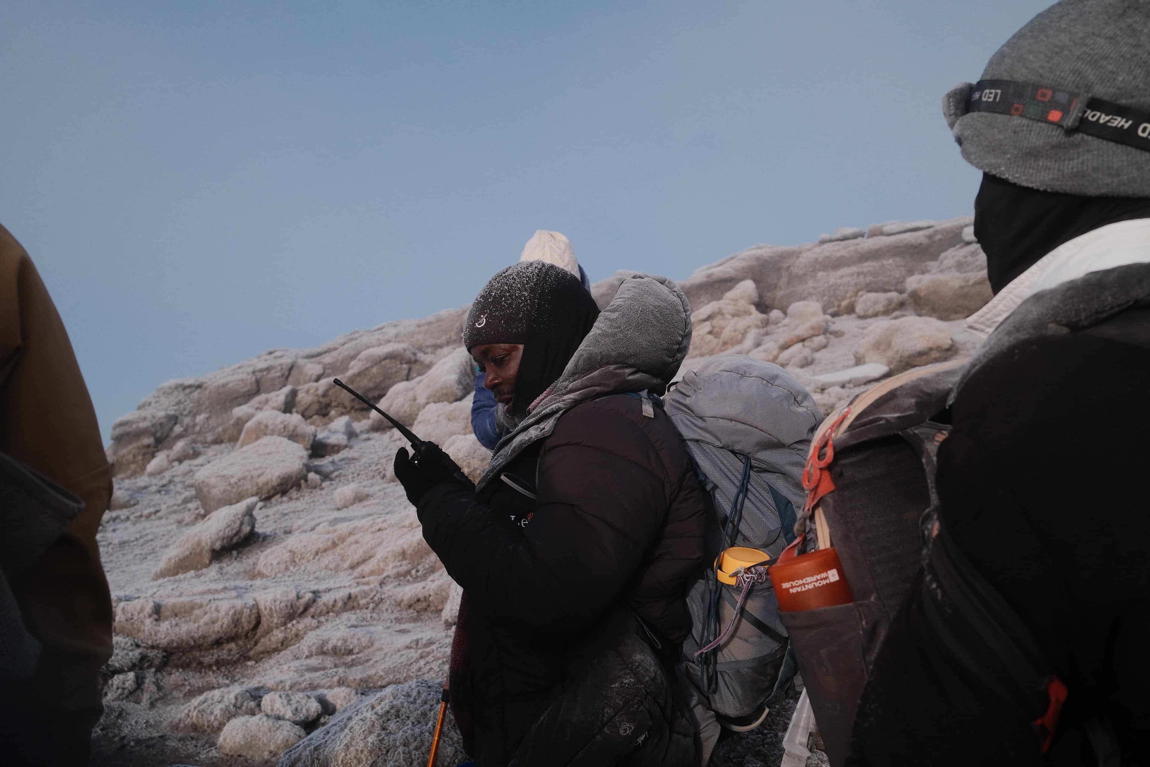 Legend Expeditions guide at Kilimanjaro summit with glacier ice formations in background