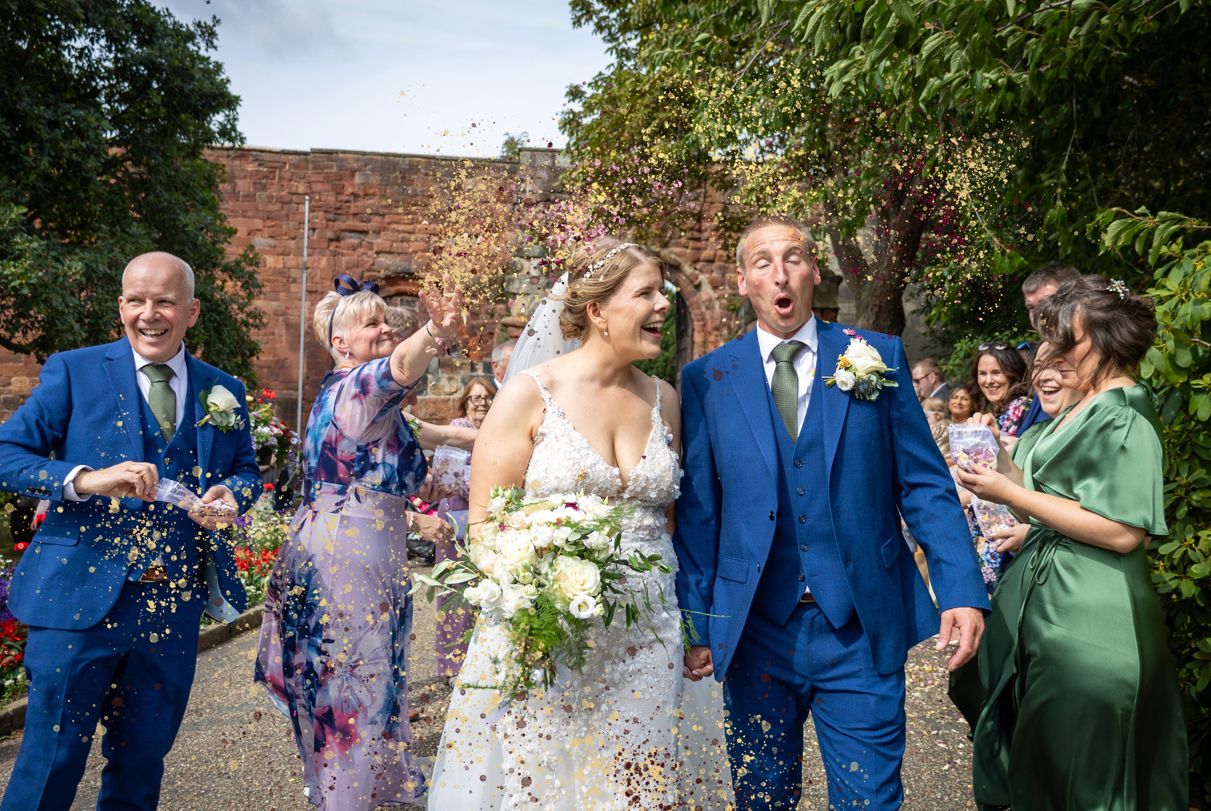 Will and Becs walking through guests throwing confetti outside Shrewsbury Castle
