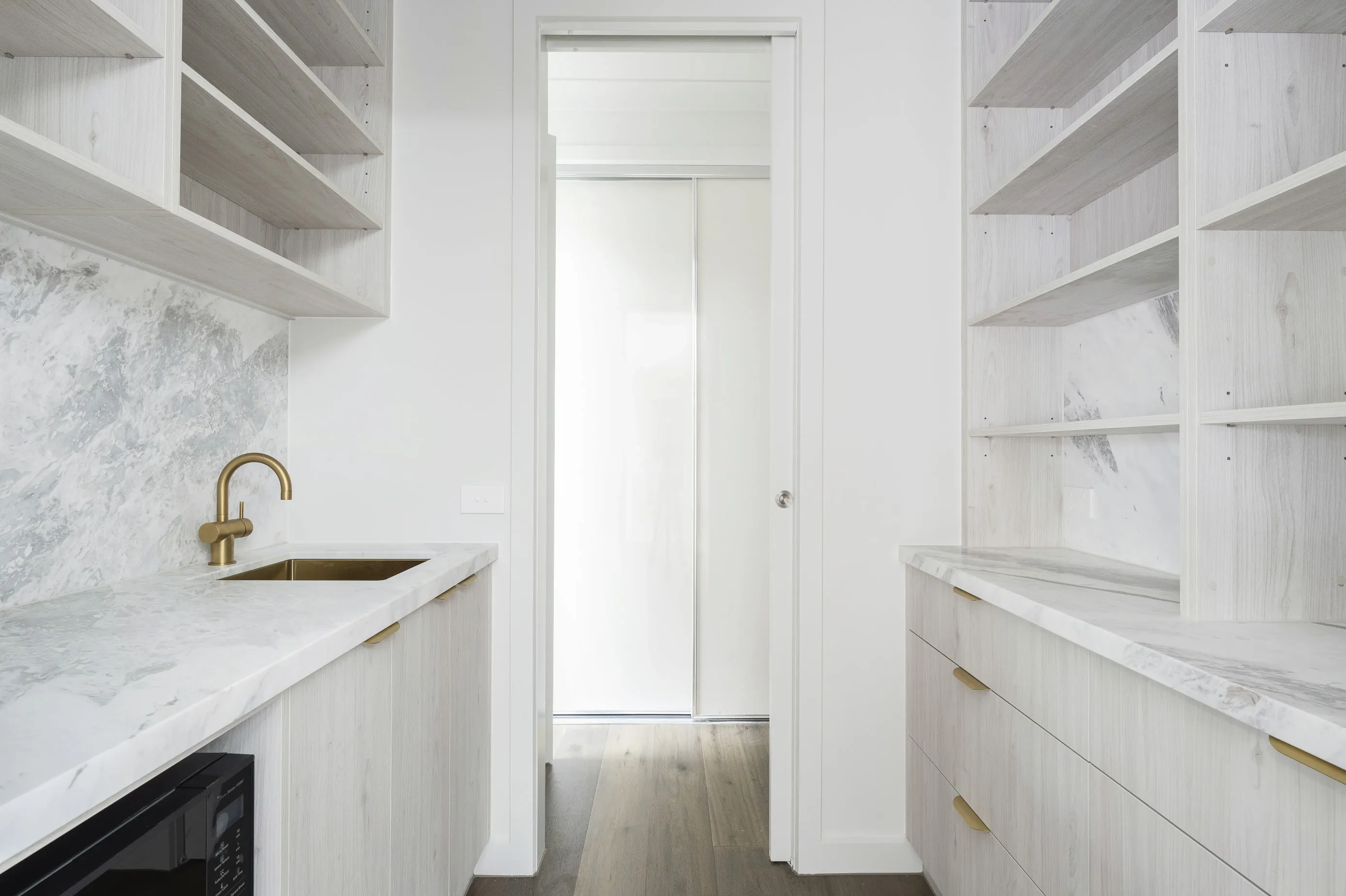 Bundoora butler’s pantry with a brushed-brass tap, marble benchtop and open whitewashed oak shelving